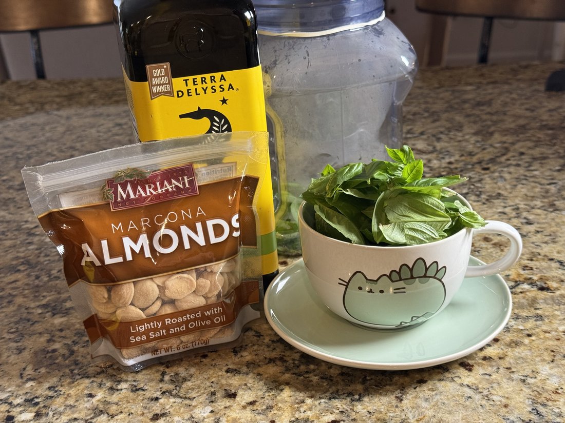 Marcona almonds, Terra Delyssa olive oil, and fresh basil leaves ready for pesto