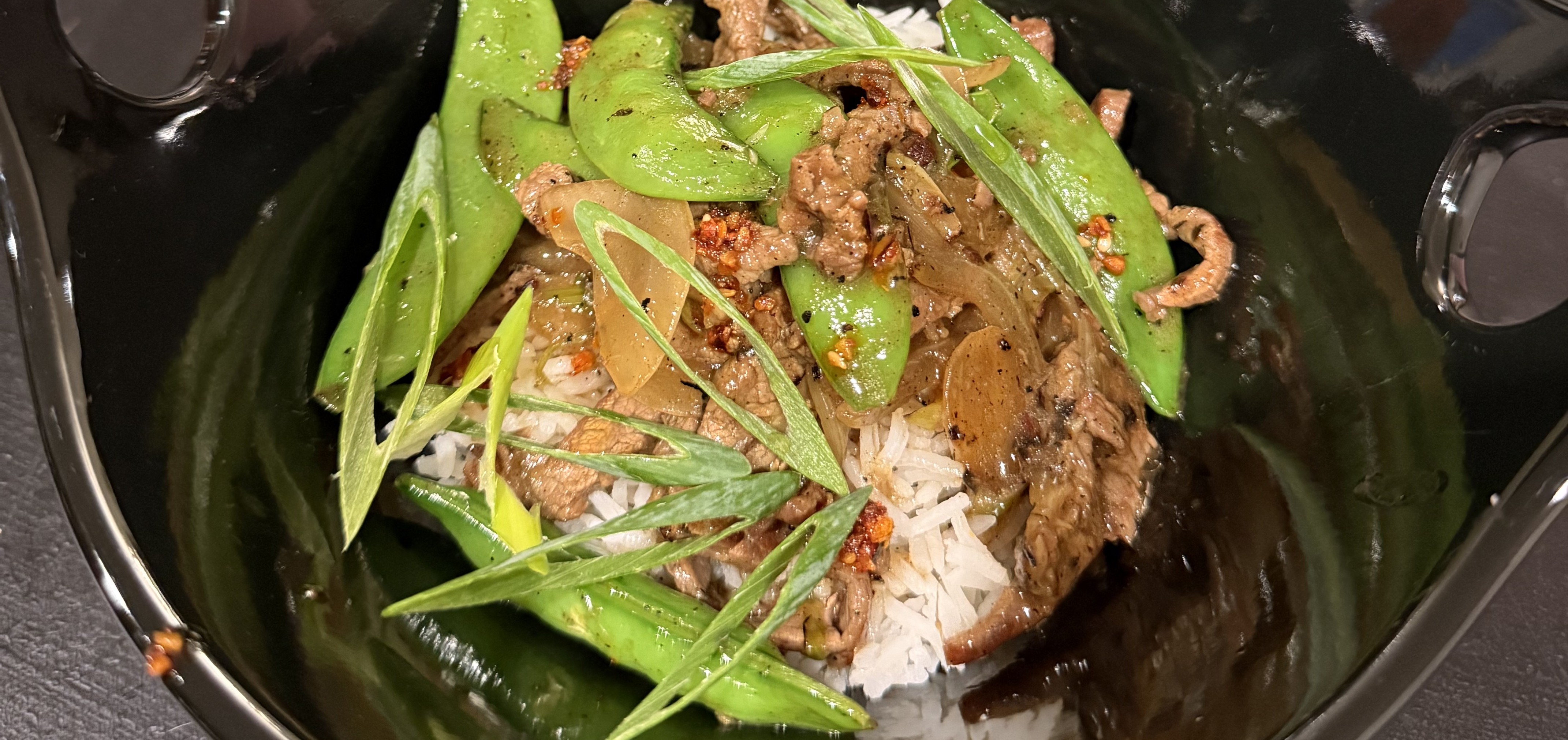 Glossy beef and sugar snap pea stir fry over jasmine rice