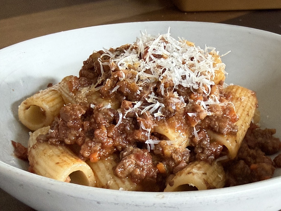 The finished bolognese spooned over rigatoni and topped with freshly grated Parmesan