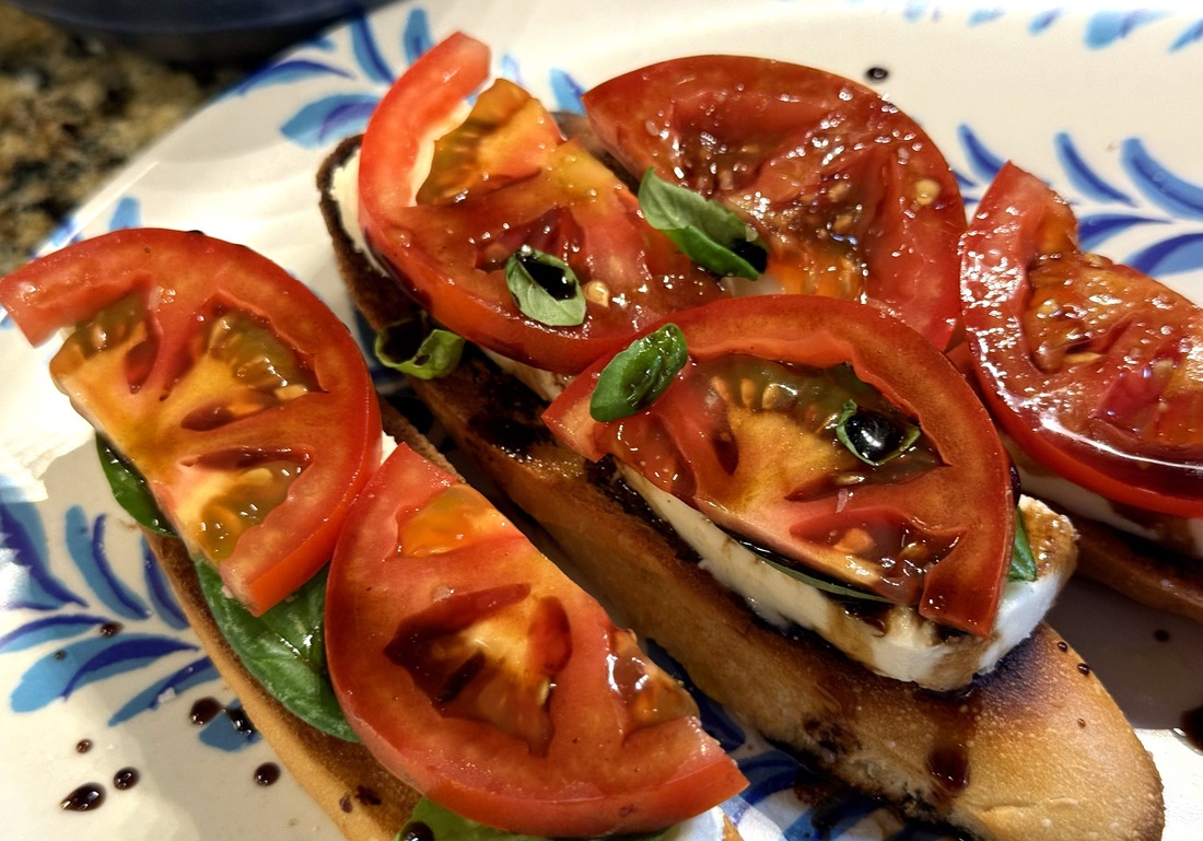 Bruschetta caprese on a blue and white plate, tomatoes and basil over toasted bread with balsamic