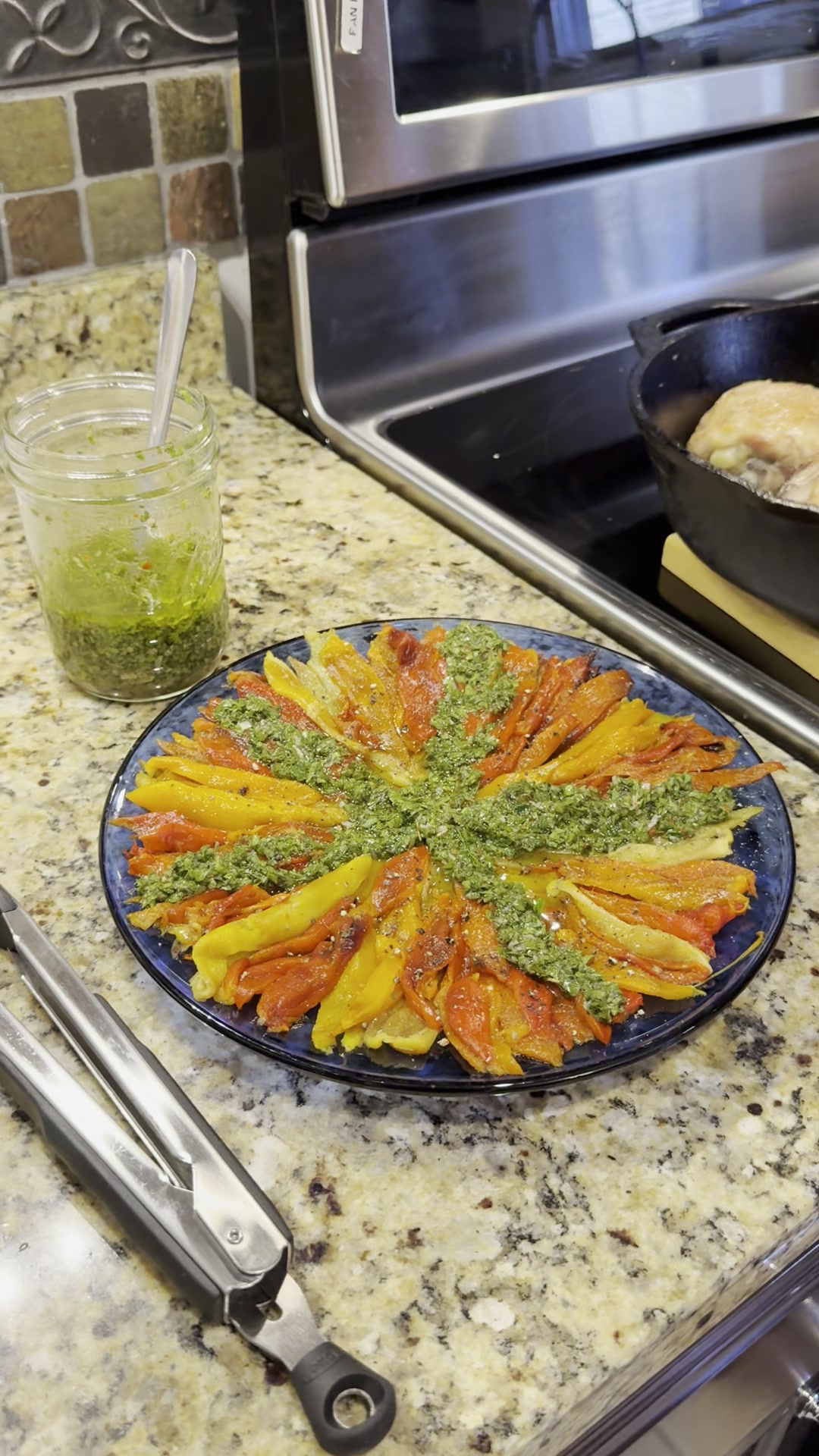 Roasted bell peppers fanned on a platter with bright green chimichurri drizzled over the top