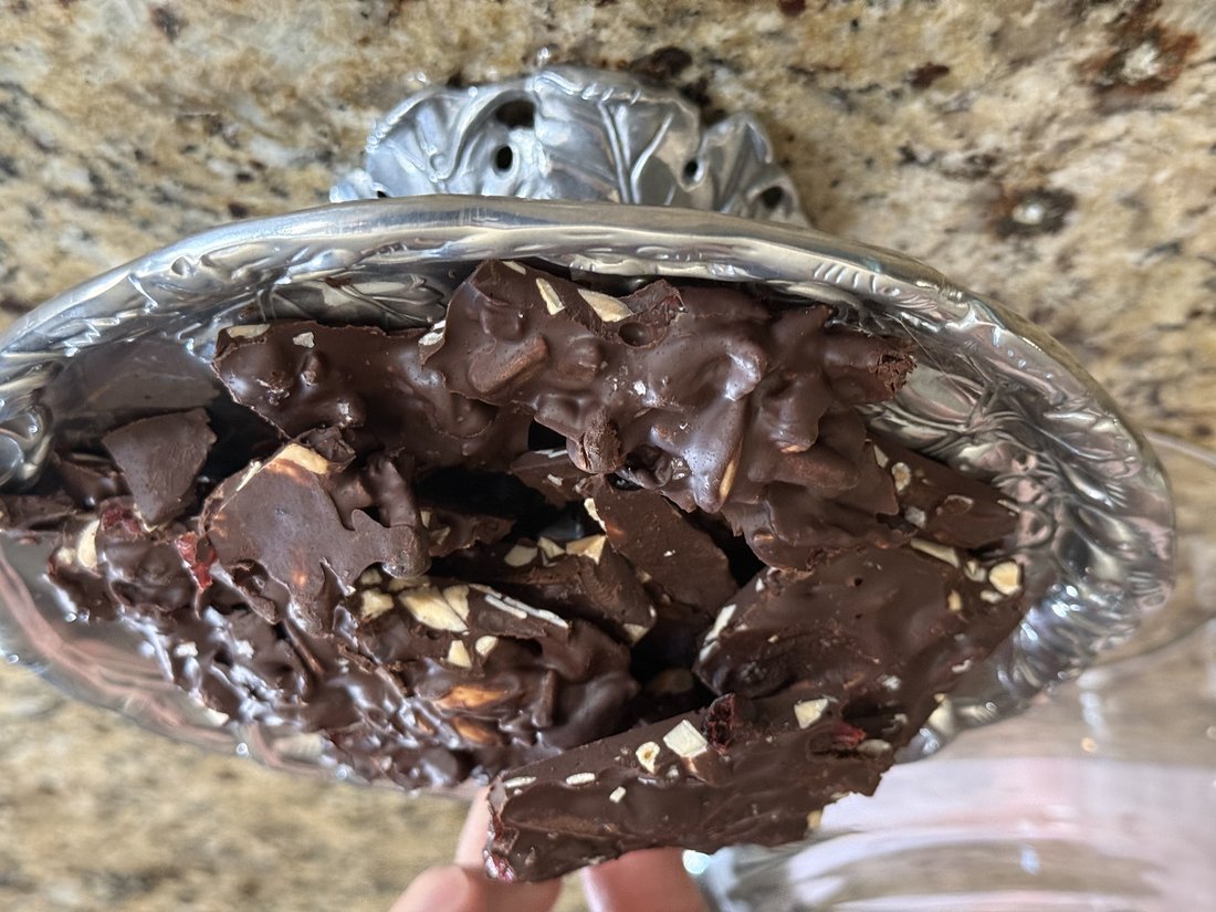 Dark chocolate bark broken into rustic pieces, piled on a silver pedestal cake stand
