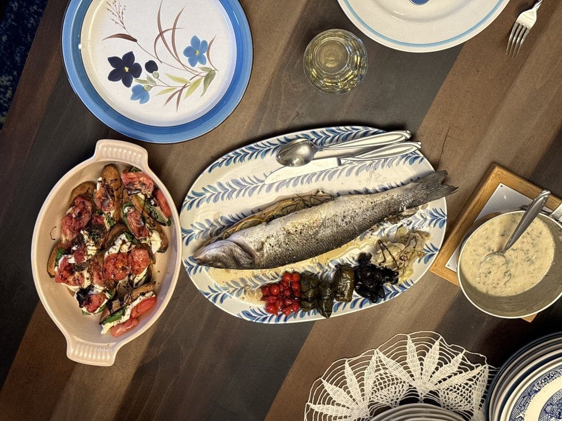Whole roasted branzino at the table with tarragon beurre blanc, lemon, and fresh herbs