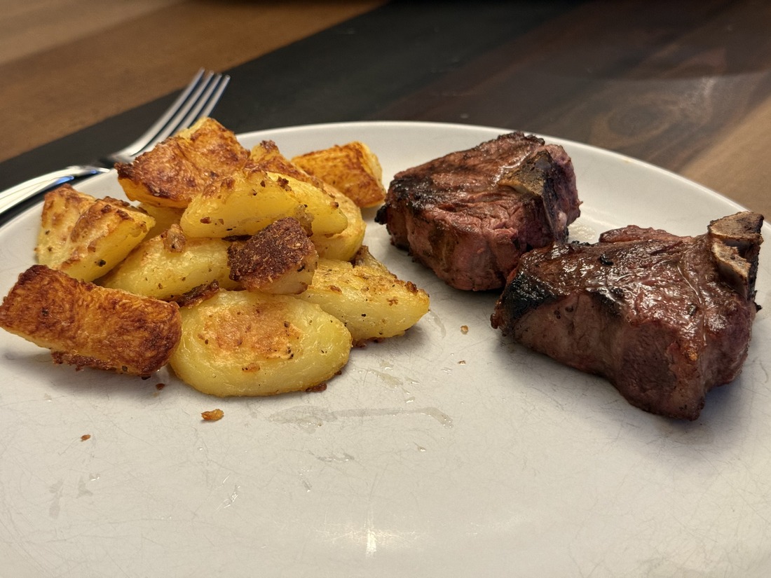 Grilled lamb loin chops plated alongside golden potatoes roasted in duck fat