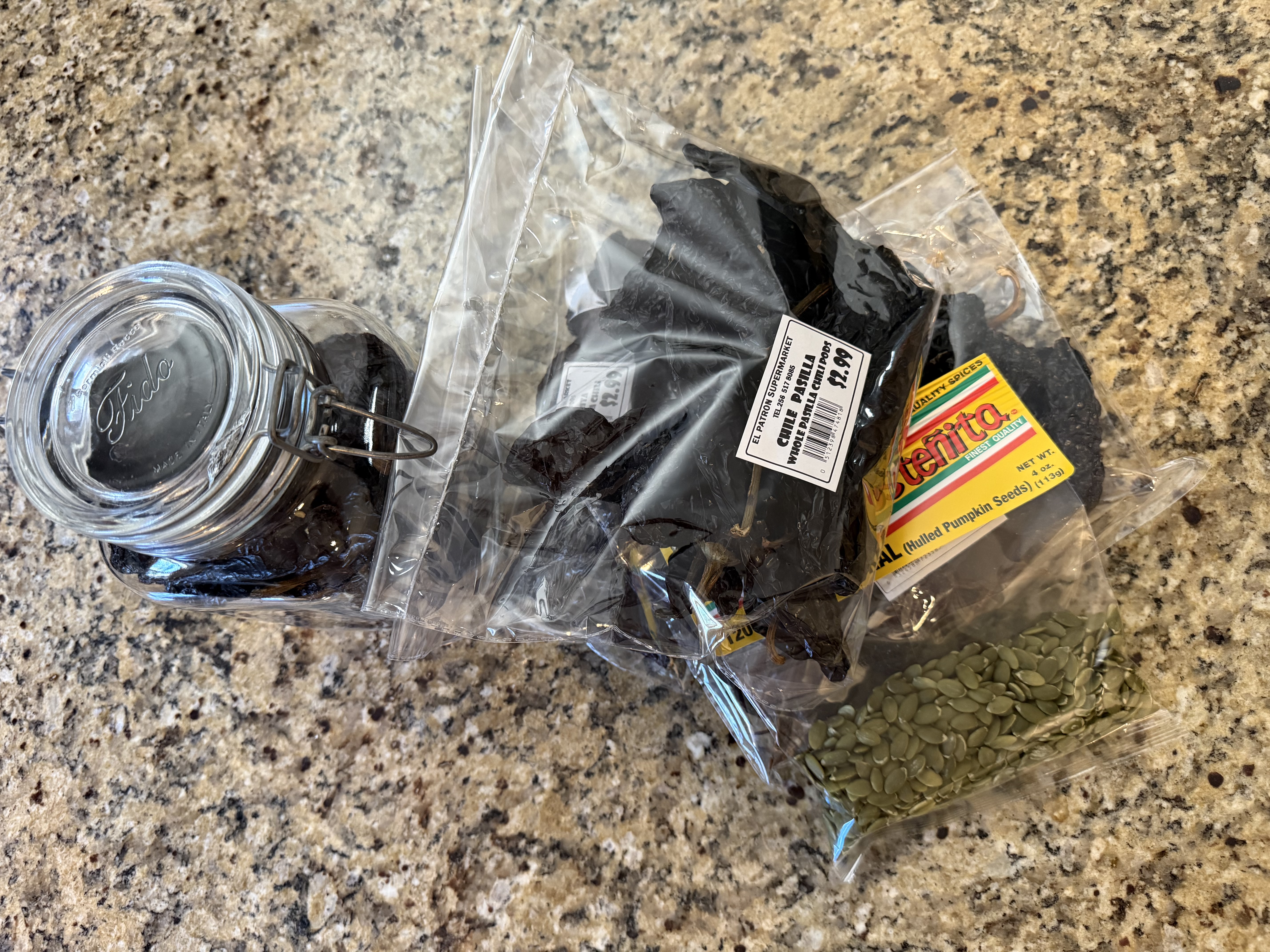 Dried chiles in a mason jar and bags of pepitas and chiles — the mole pantry