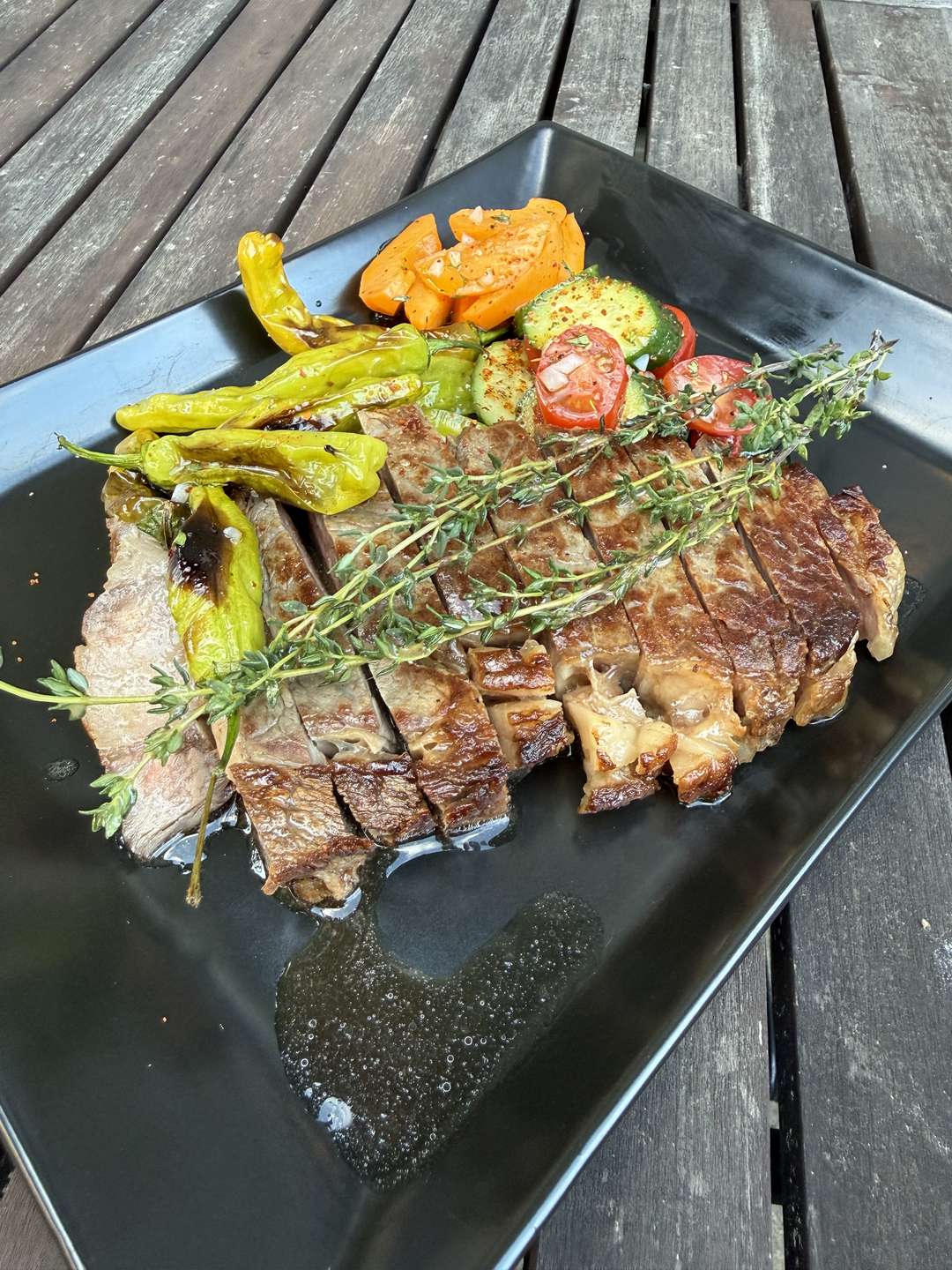 Cucumber-tomato salad Tajin style served beside a sliced seared ribeye and blistered shishito peppers