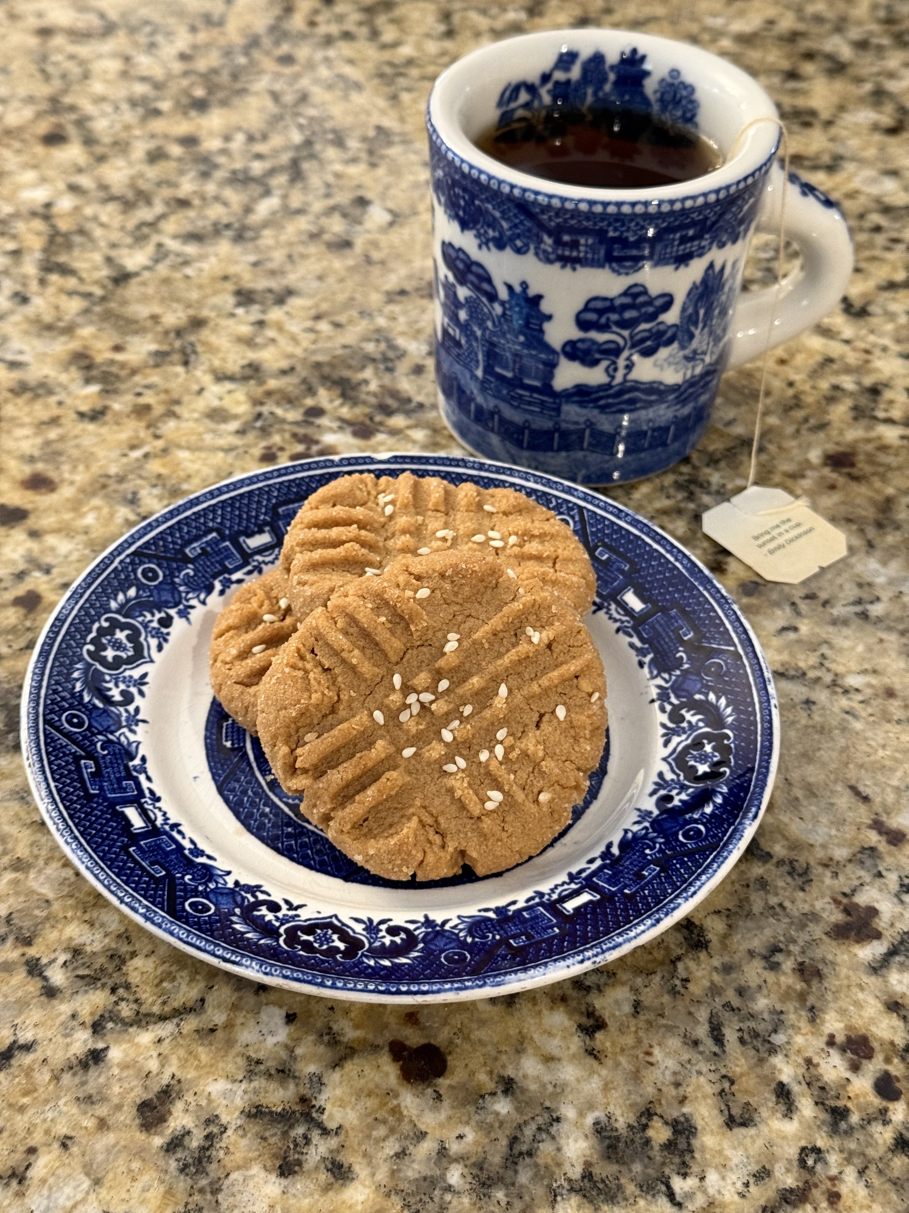 Peanut butter cookies with sesame seeds on a blue and white plate with tea
