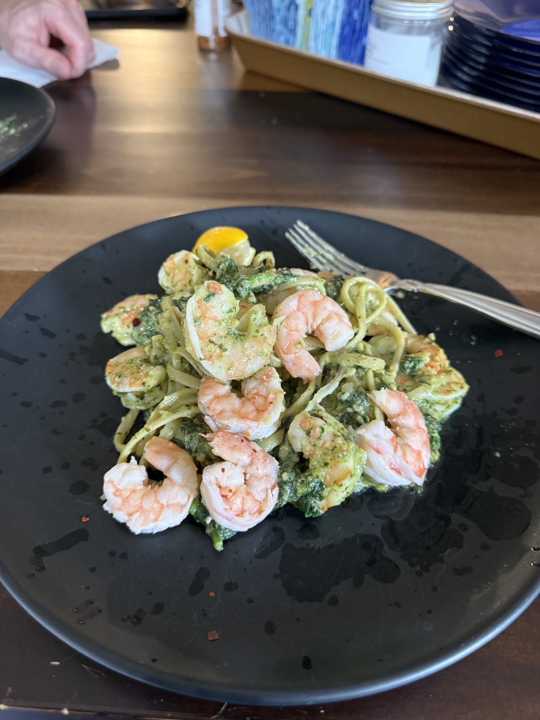 Pesto shrimp and spinach pasta on a dark slate plate