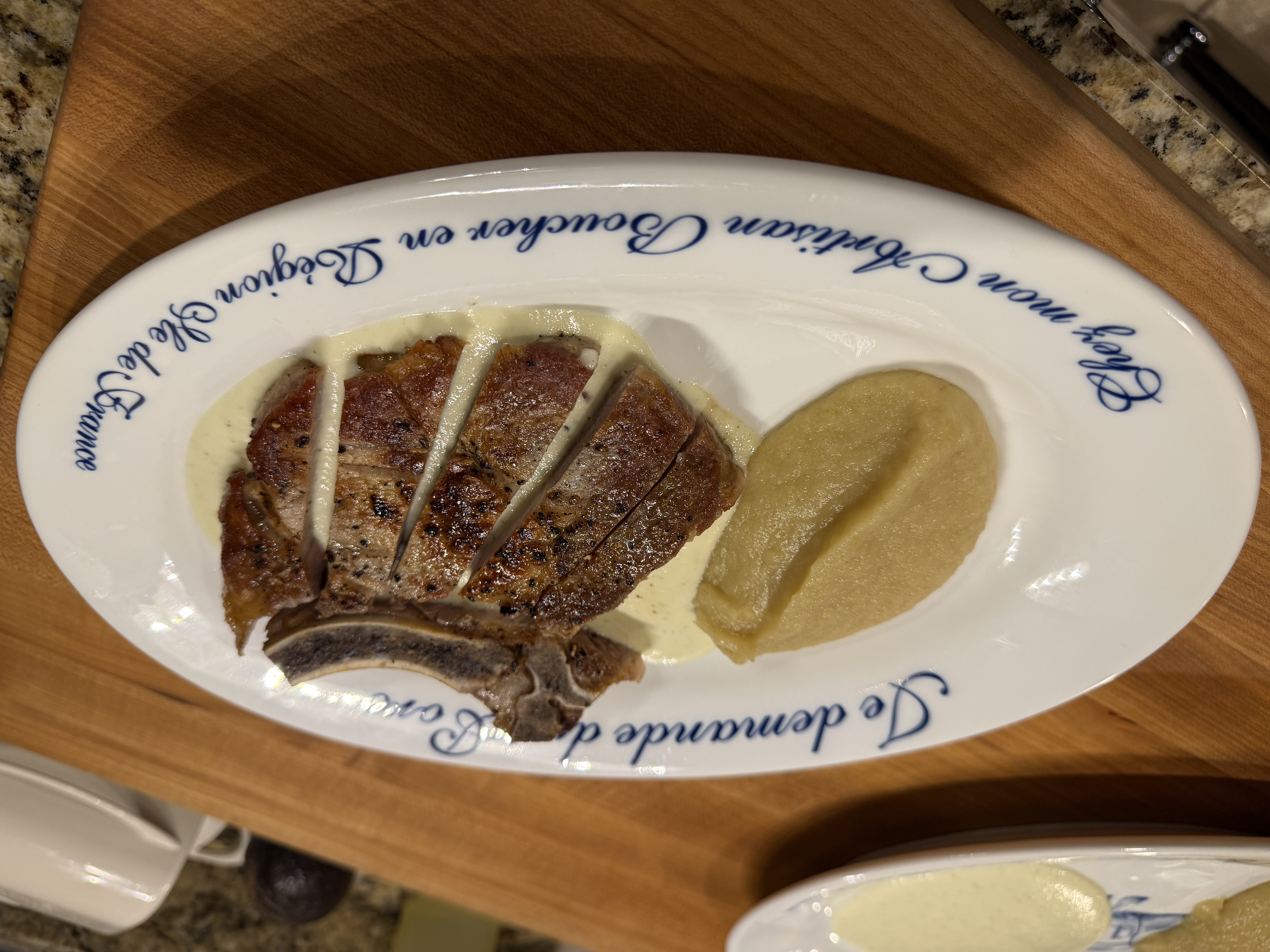 Sliced pork chop on soubise cream with baked apple sauce on a French butcher plate