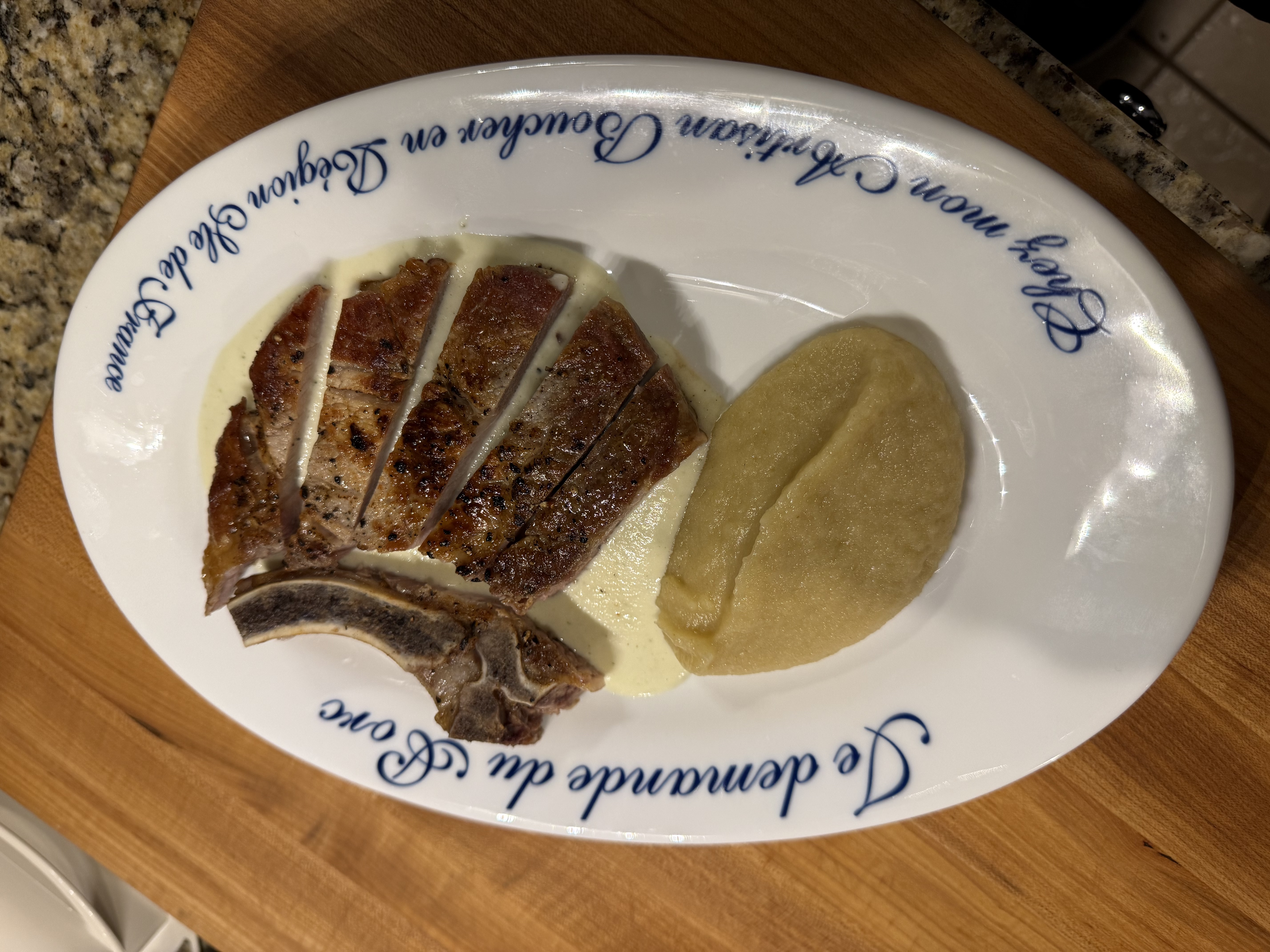 Pork chop plated with soubise and apple sauce — pulled back view showing the full plate