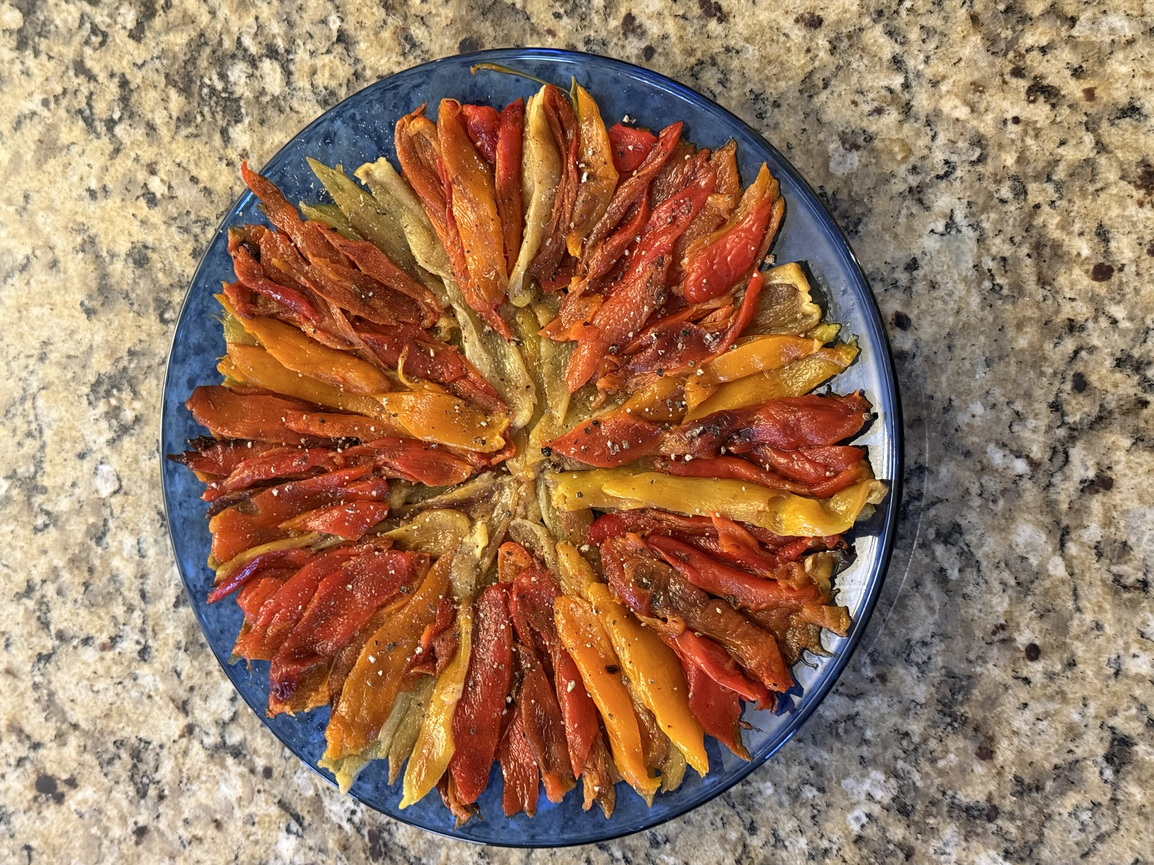 Roasted bell peppers arranged in a spiral on a blue plate