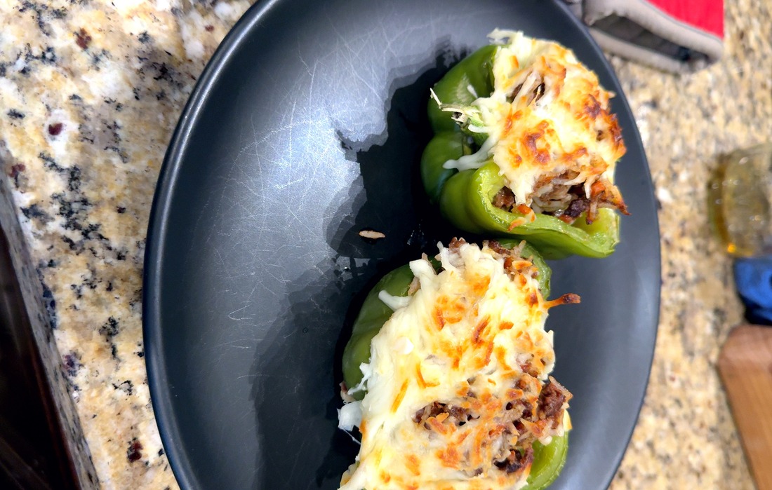 Two stuffed pepper halves plated in a dark bowl
