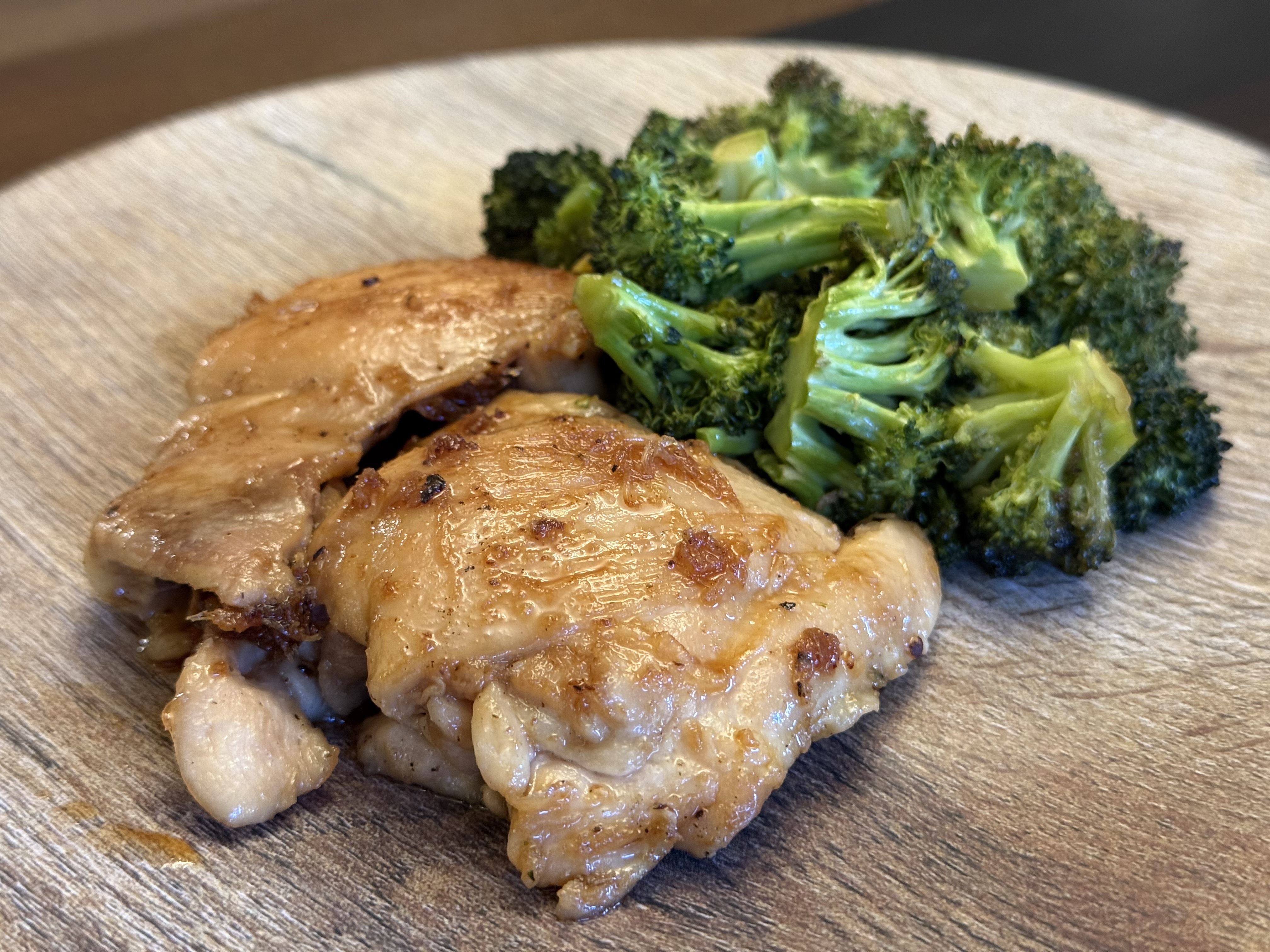 Teriyaki-glazed chicken thighs with broccoli in a wooden bowl